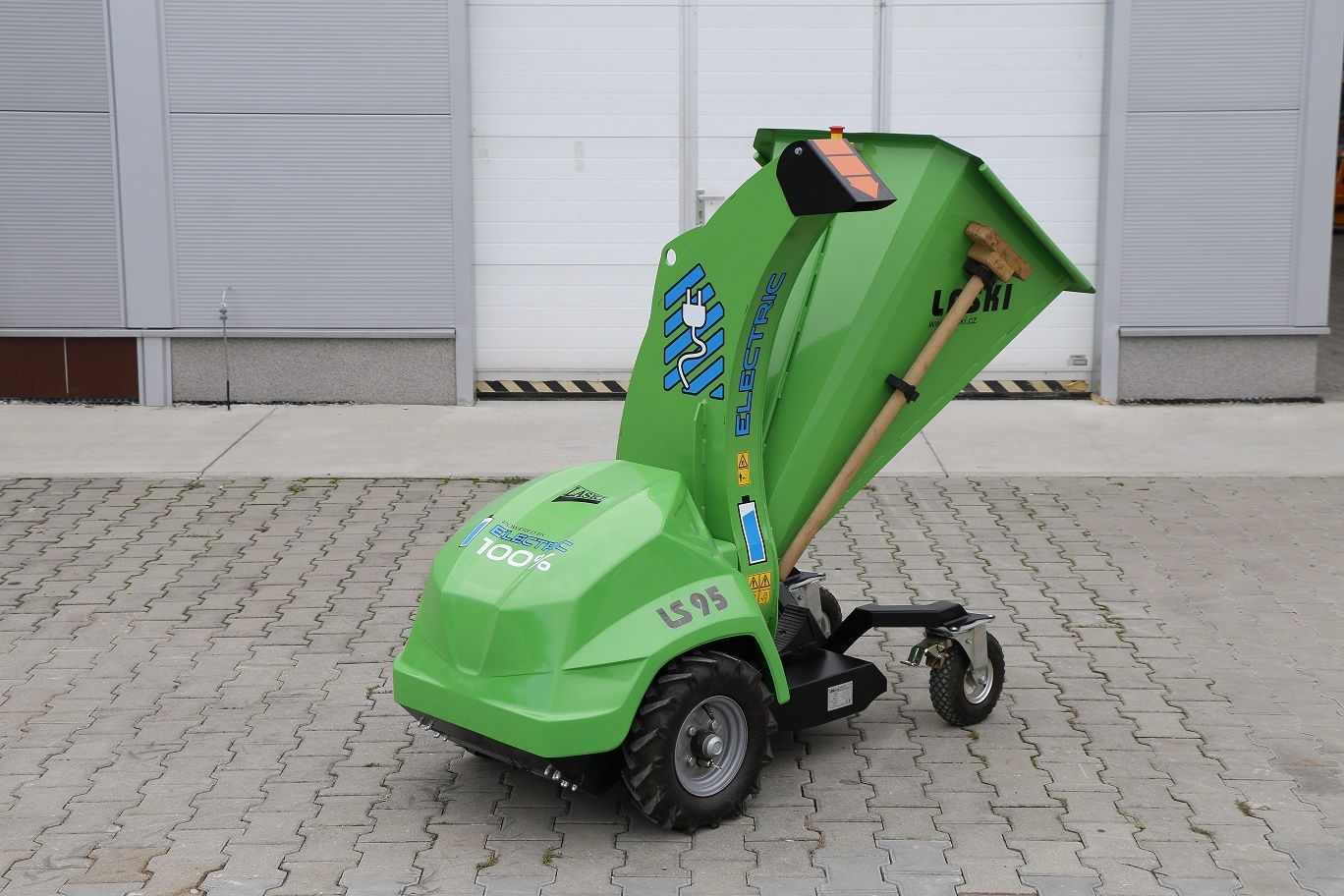Eine grüne Maschine ist auf einem gepflasterten Gehweg vor einem Gebäude geparkt.