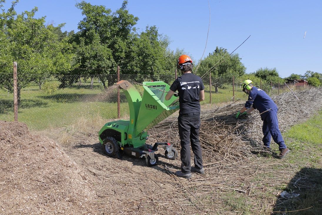 Zwei Männer stehen neben einer grünen Maschine auf einem Feld.