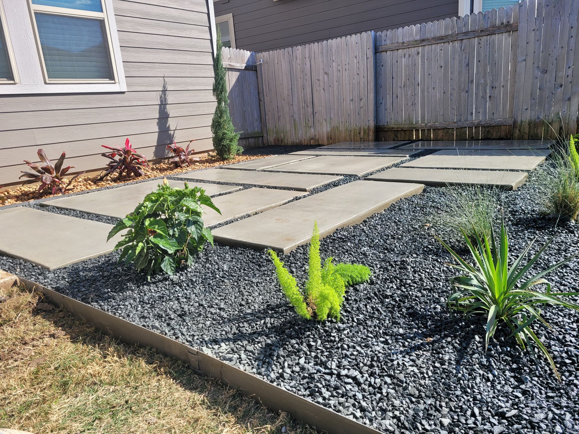 A row of bricks are sitting on the ground in a backyard next to a shed.