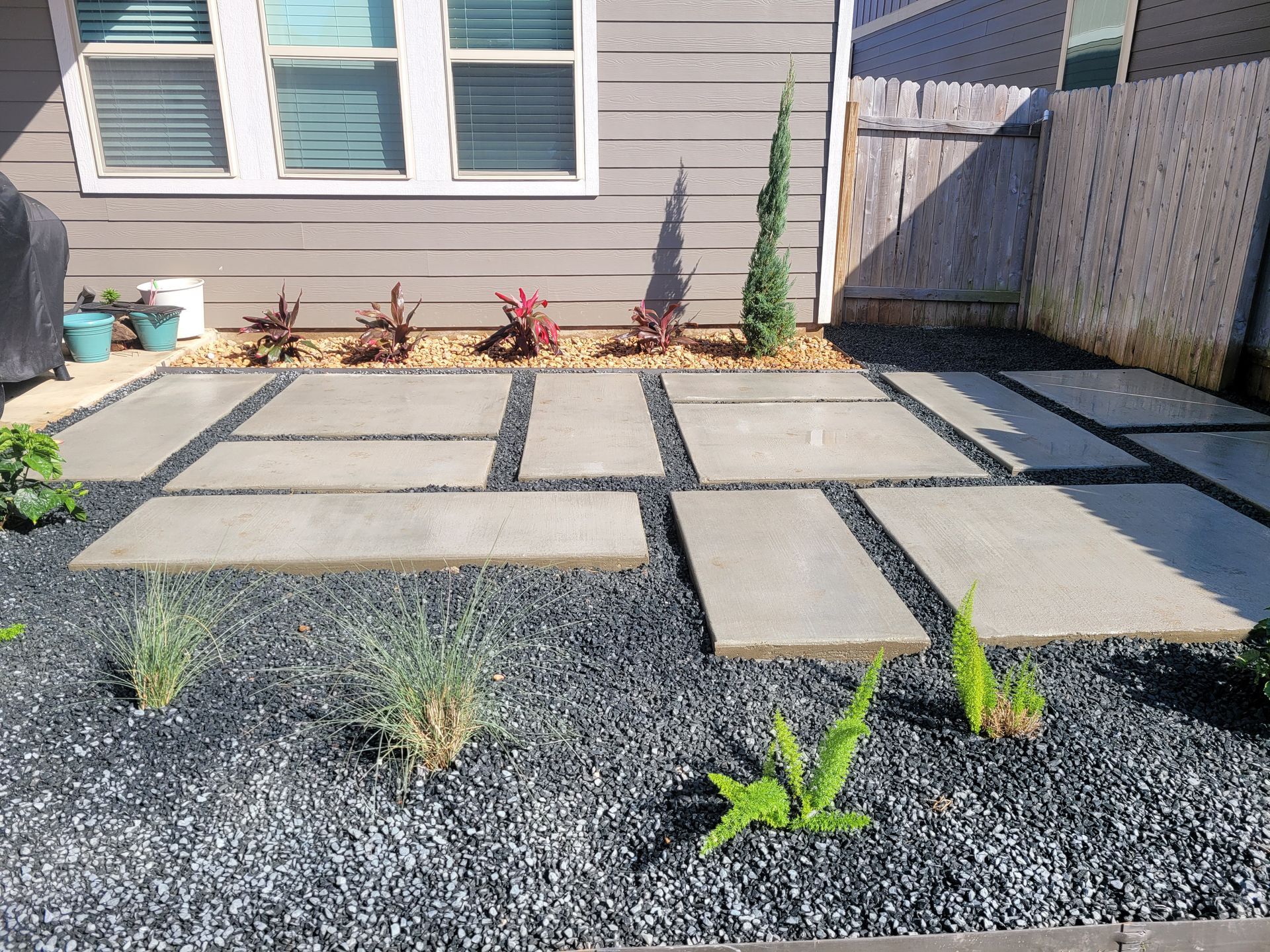 A row of bricks are sitting on the ground in a backyard next to a shed.