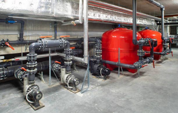 Pipes, pumps, and red tanks in an industrial setting, likely for water filtration.