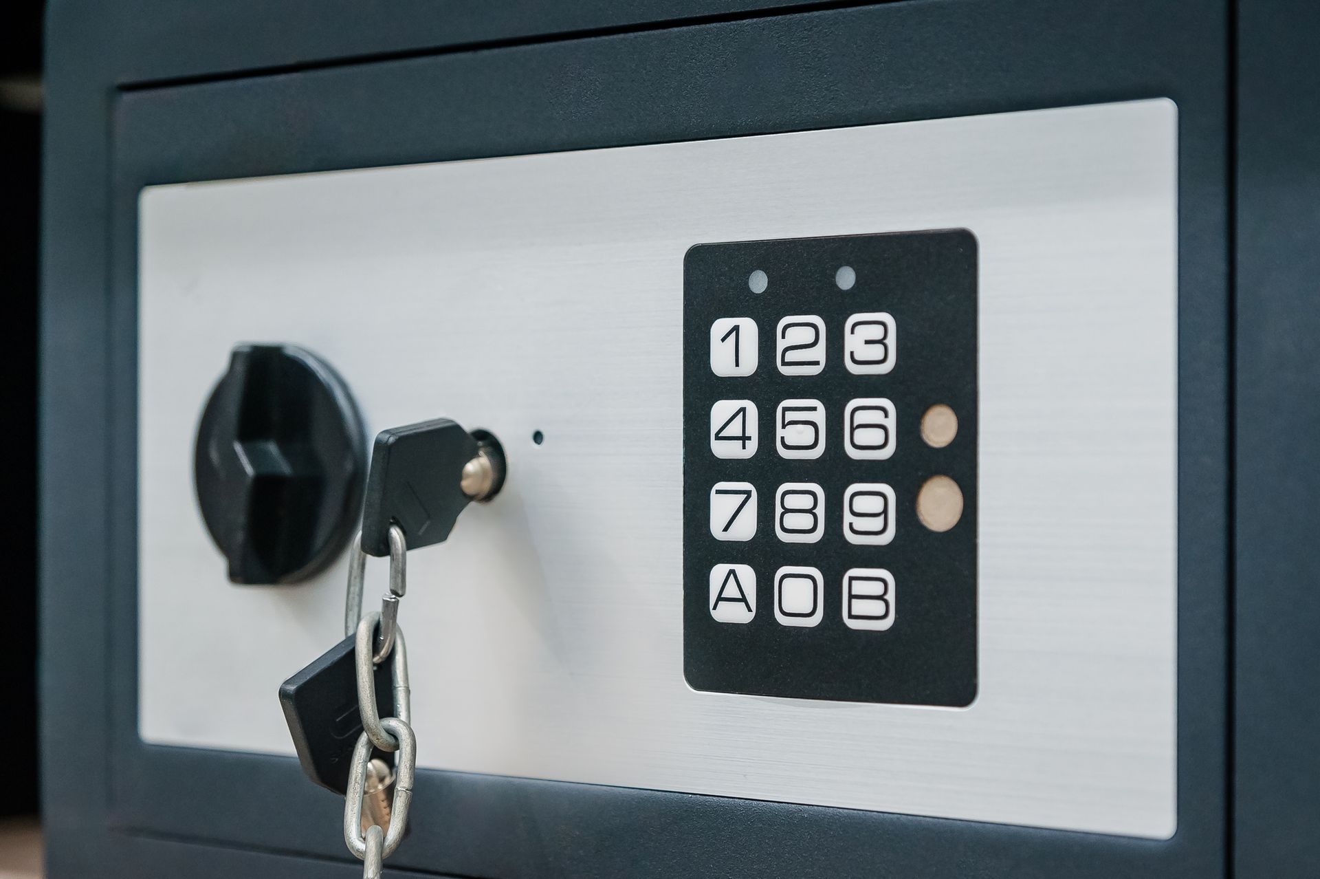 Safe with a keypad, key, and dial, in a dark gray finish.