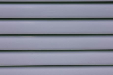 Close-up of light gray horizontal vinyl siding on an exterior wall.