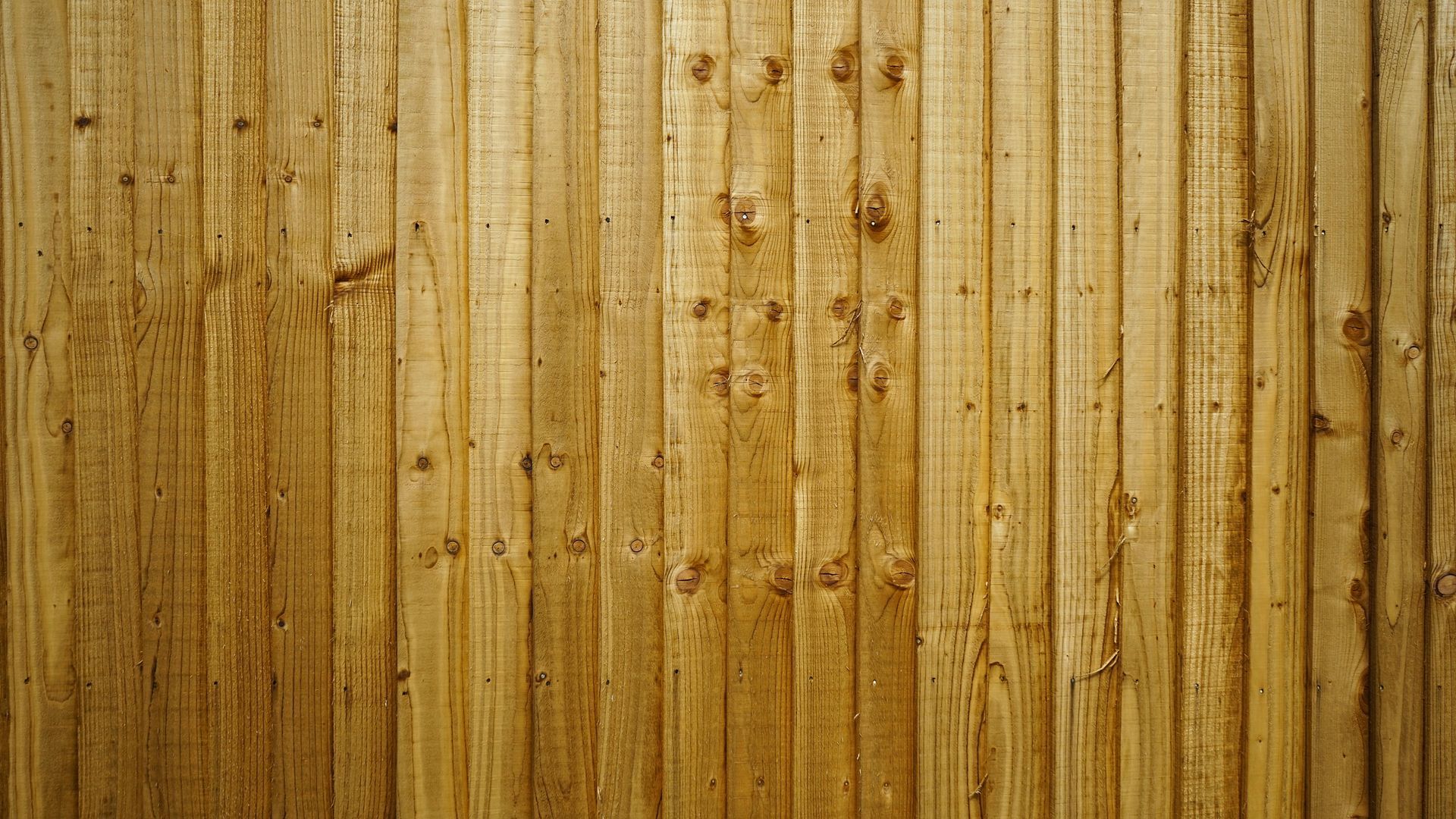 Close-up view of a rustic wooden fence made of vertical brown planks with visible wood grain and knots.