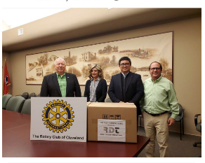 A group of people standing around a table with a sign that says the rotary club of cleveland
