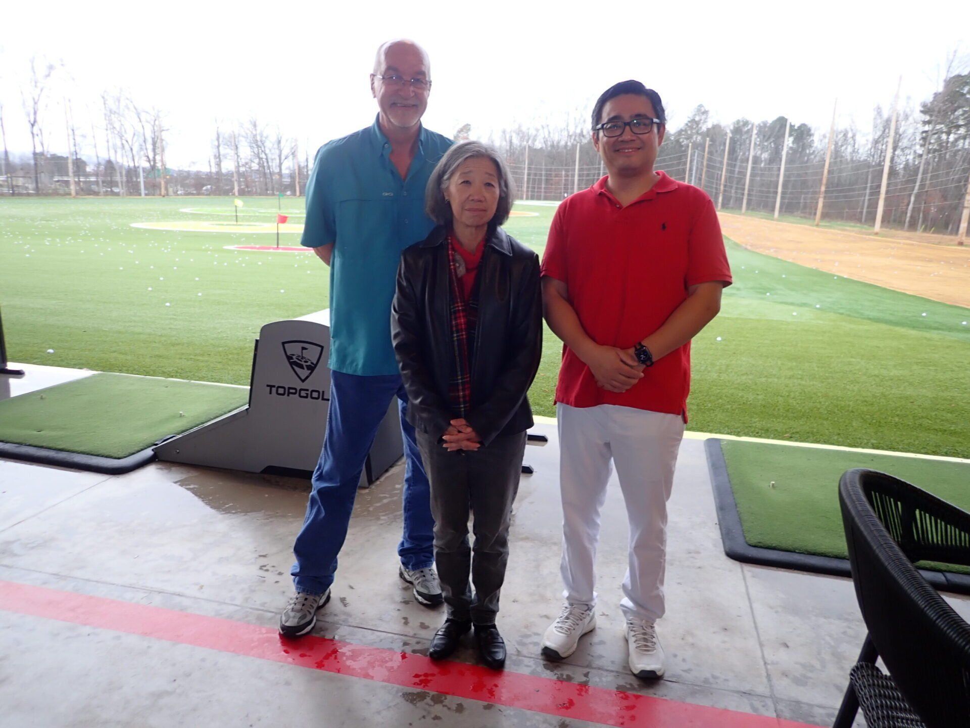 Three people are standing next to each other on a golf course.