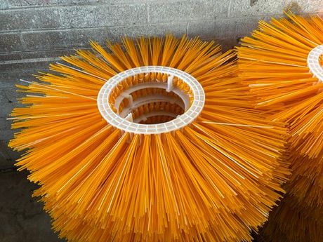 Orange and black cylindrical wire brush wheel with a metal center hole