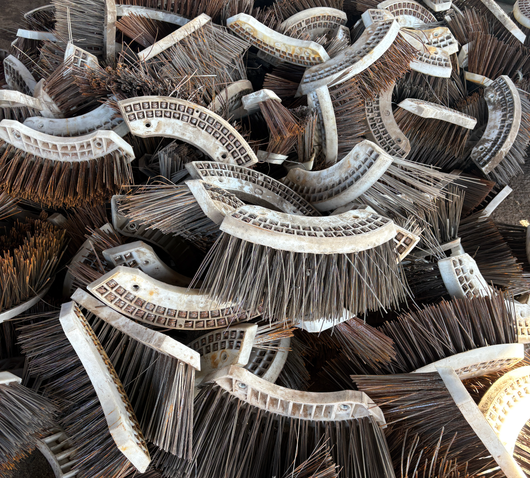 Pile of brown and white curved wire brushes stacked together