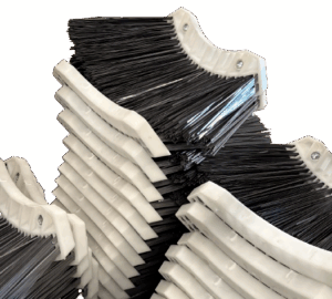 Stacked black and white cleaning brushes with curved bristles on a white background