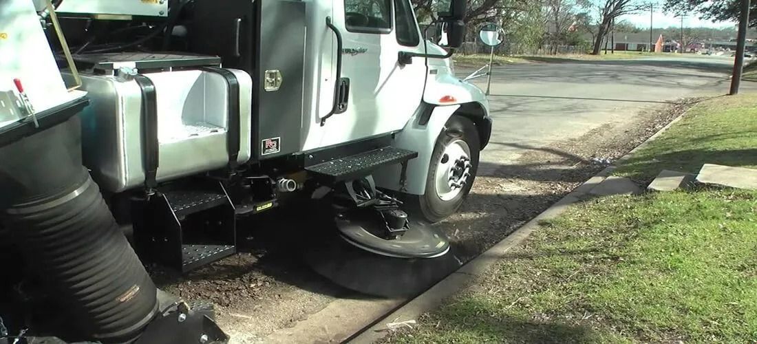 Semi-truck parked on a roadside shoulder beside grass and pavement, with fuel tank and steps visible.
