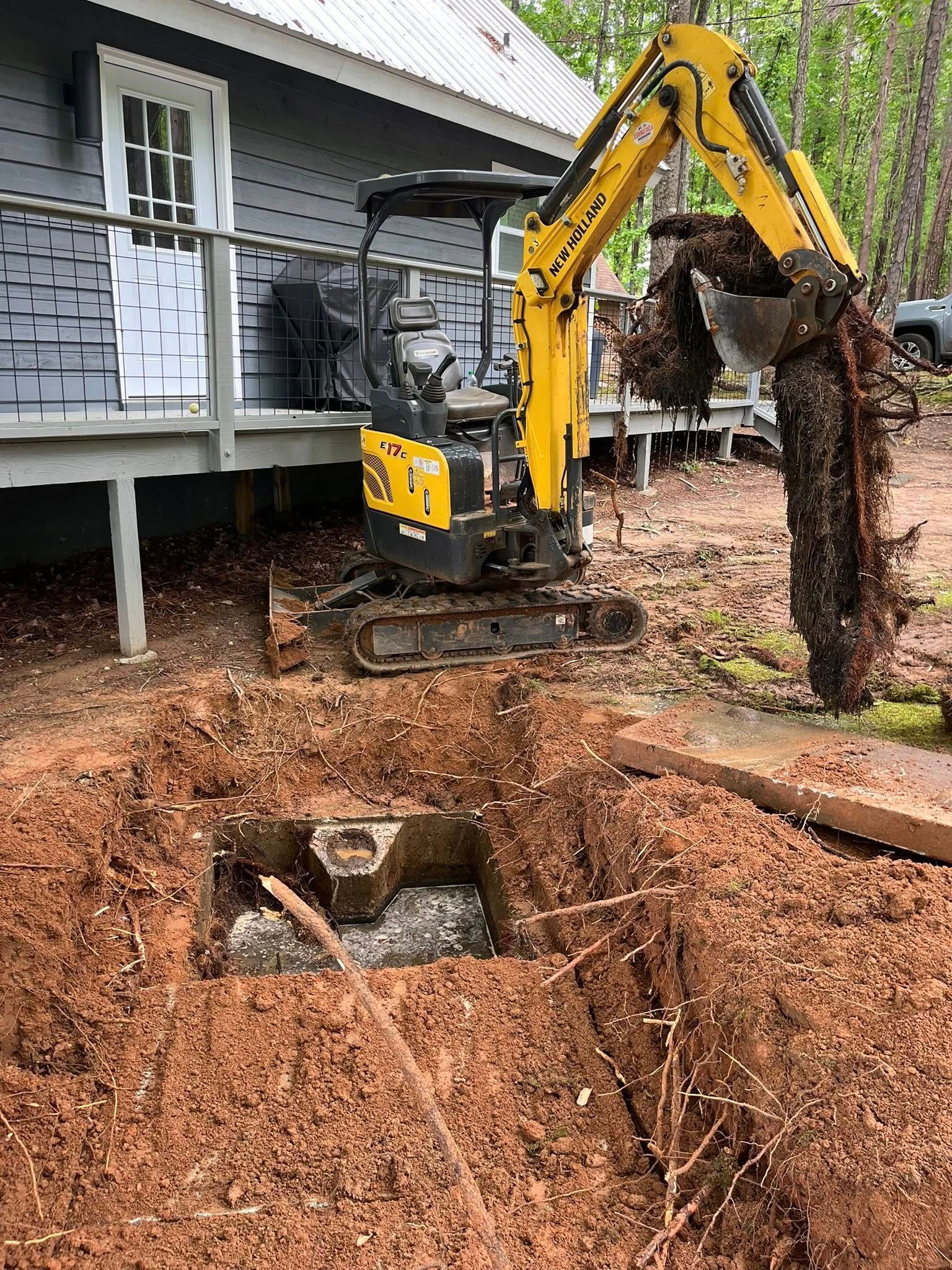 A yellow excavator is digging a hole in the ground in front of a house.