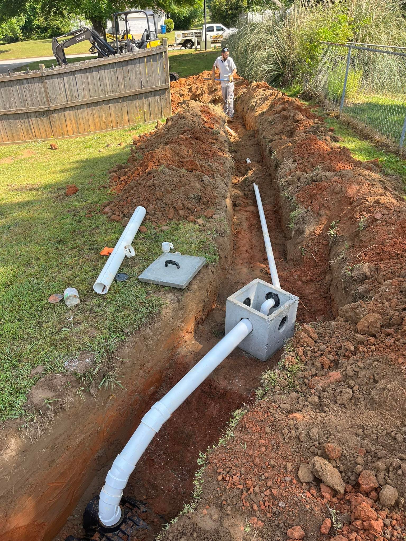 A man is digging a hole in the ground to install a septic system.