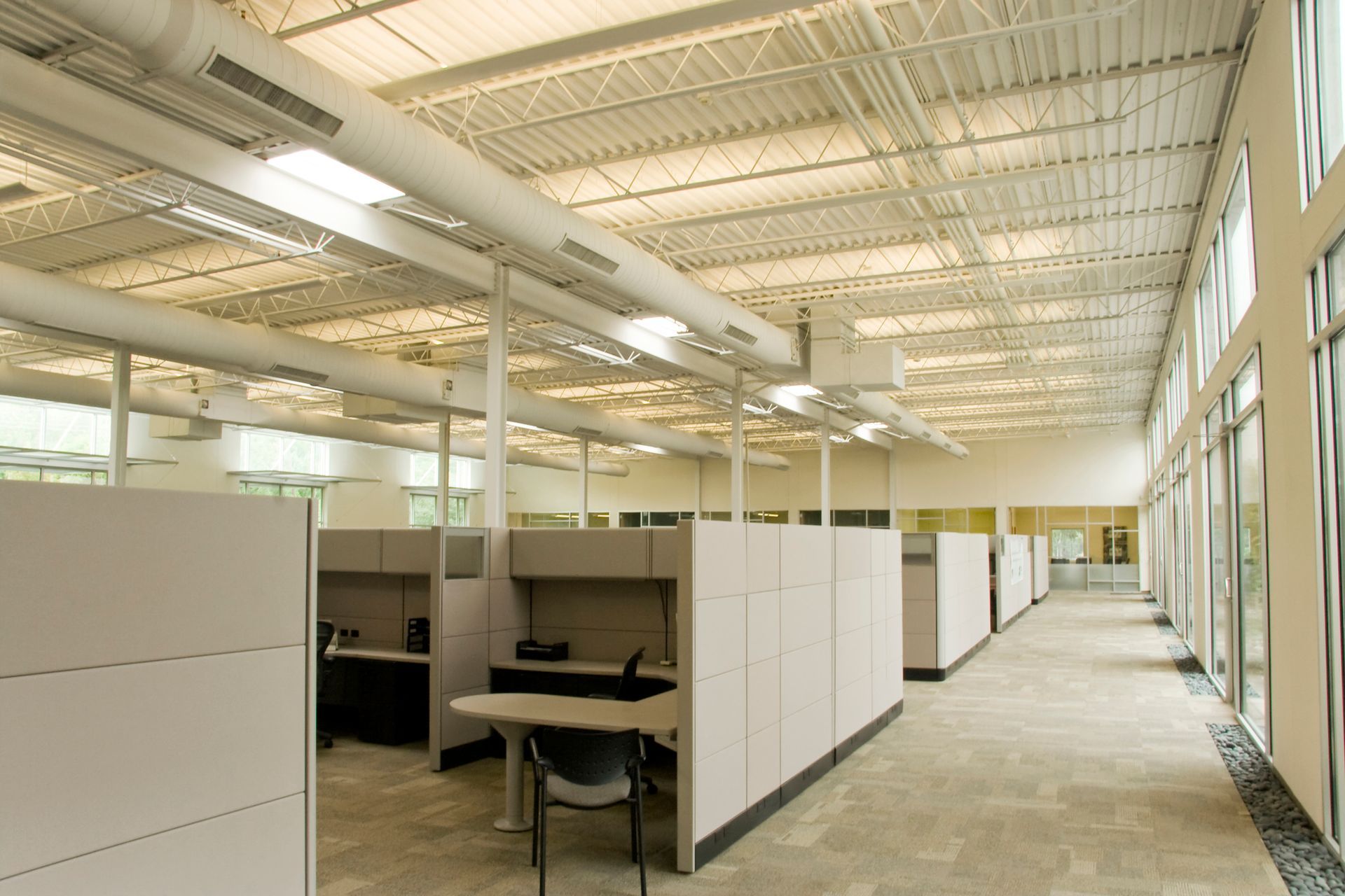 A large office with cubicles and a lot of windows