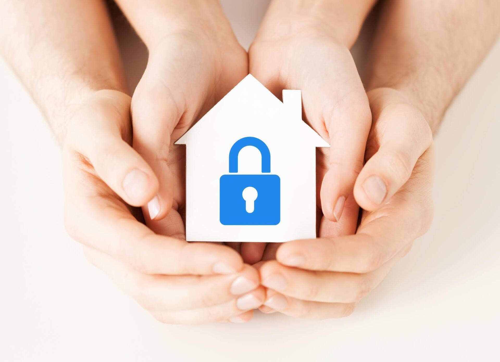A family is holding a paper house with a padlock on it.