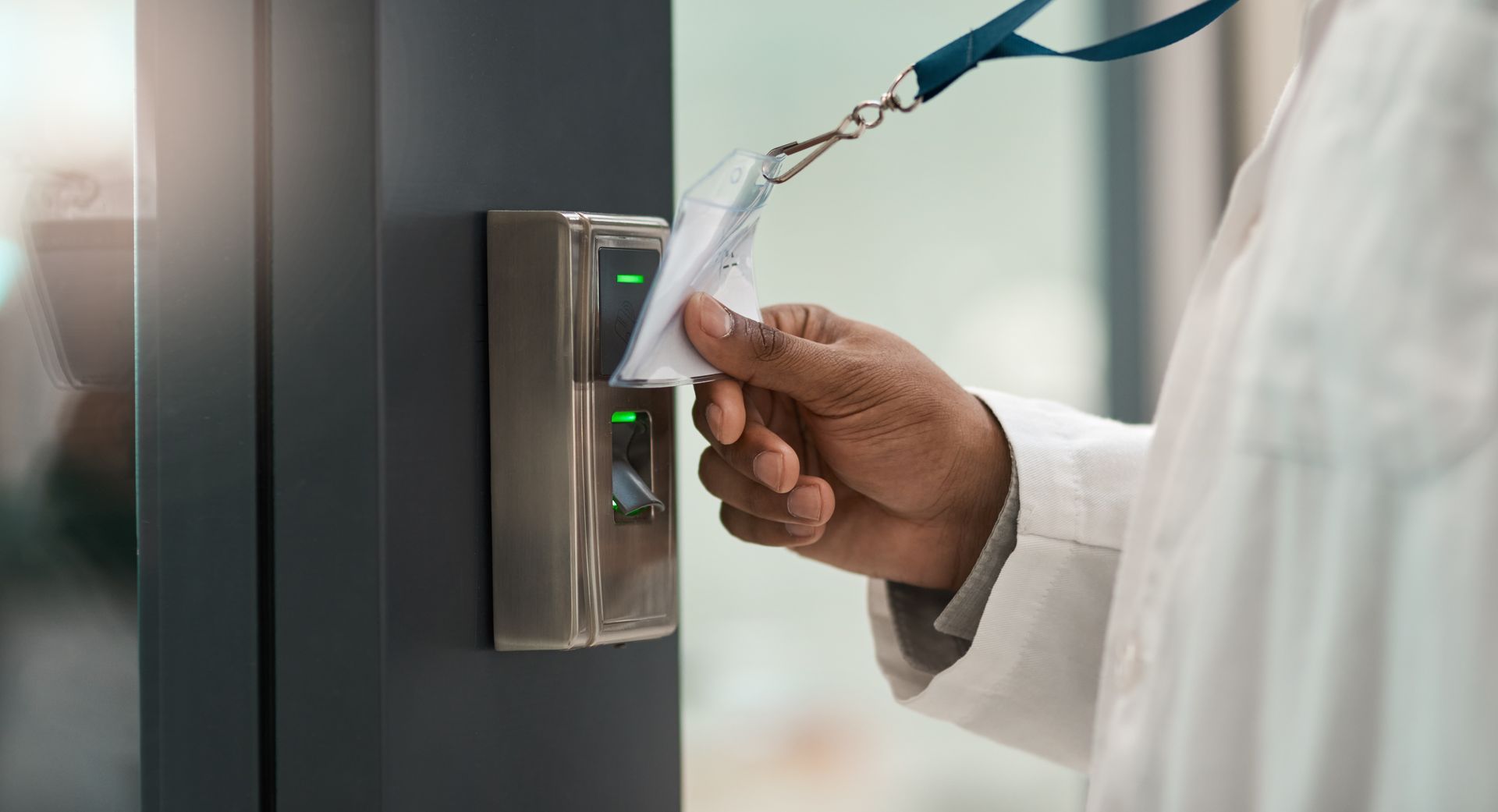 Hand using a biometric fingerprint scanner on a secure access panel