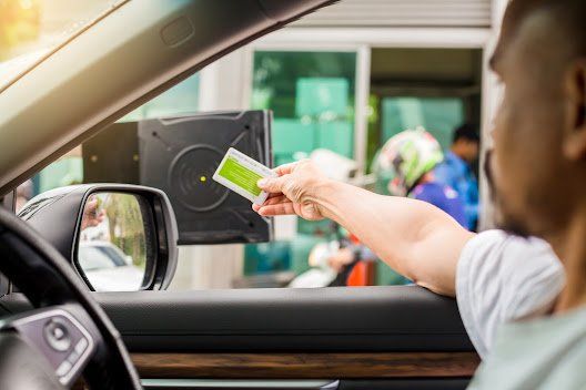 A man is holding a credit card in his hand while driving a car.
