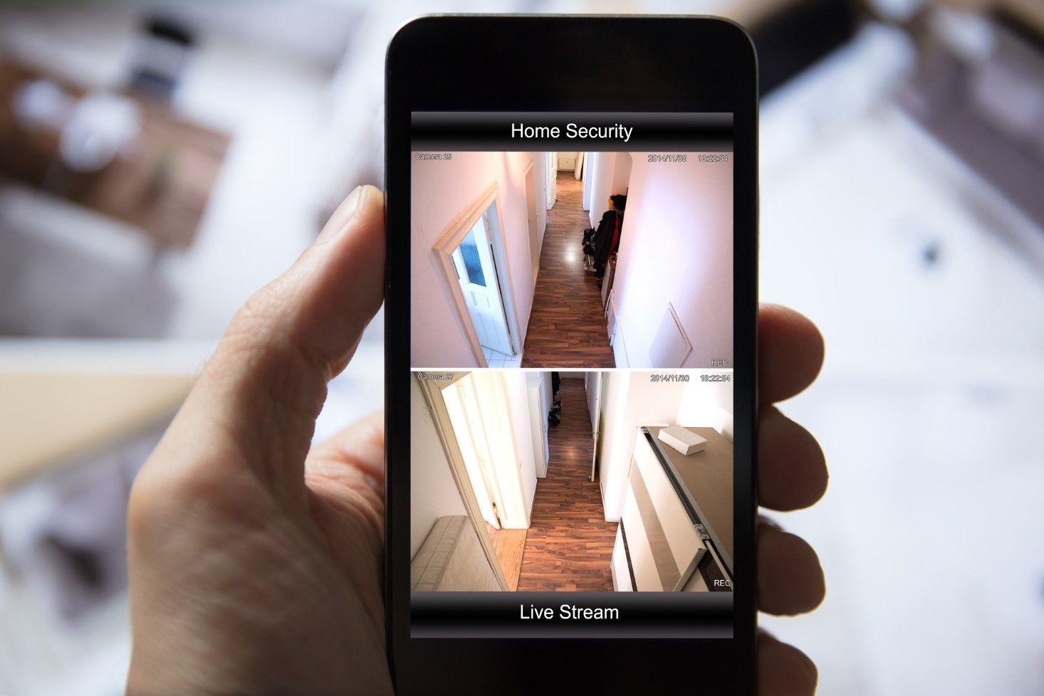 A person is holding a cell phone with a picture of a hallway on the screen