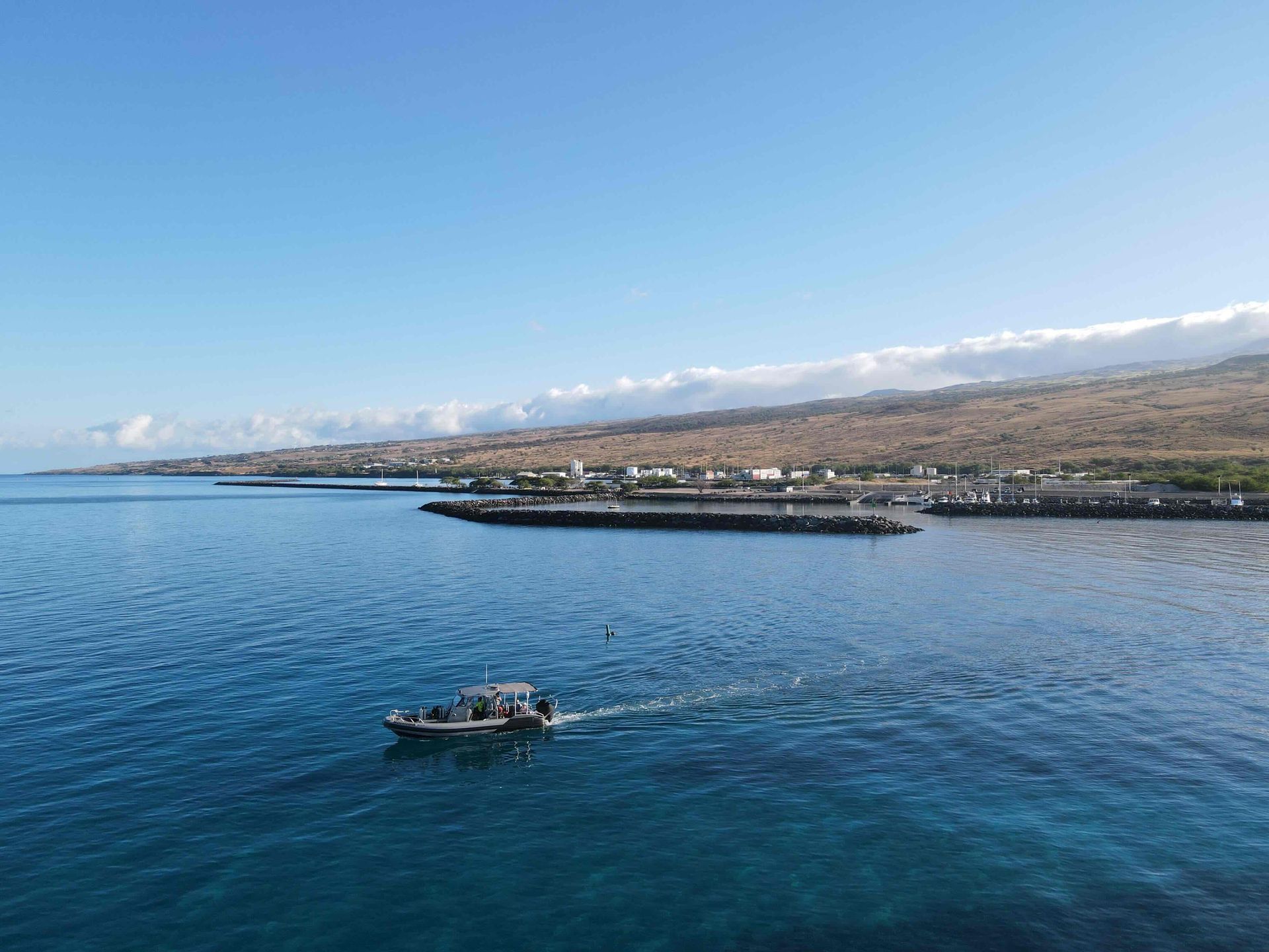 Small boat on calm blue ocean near a coastline under a clear sky