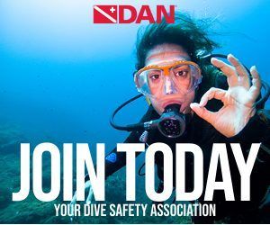 DAN dive safety ad: diver in mask underwater, making OK sign, with “JOIN TODAY” text.