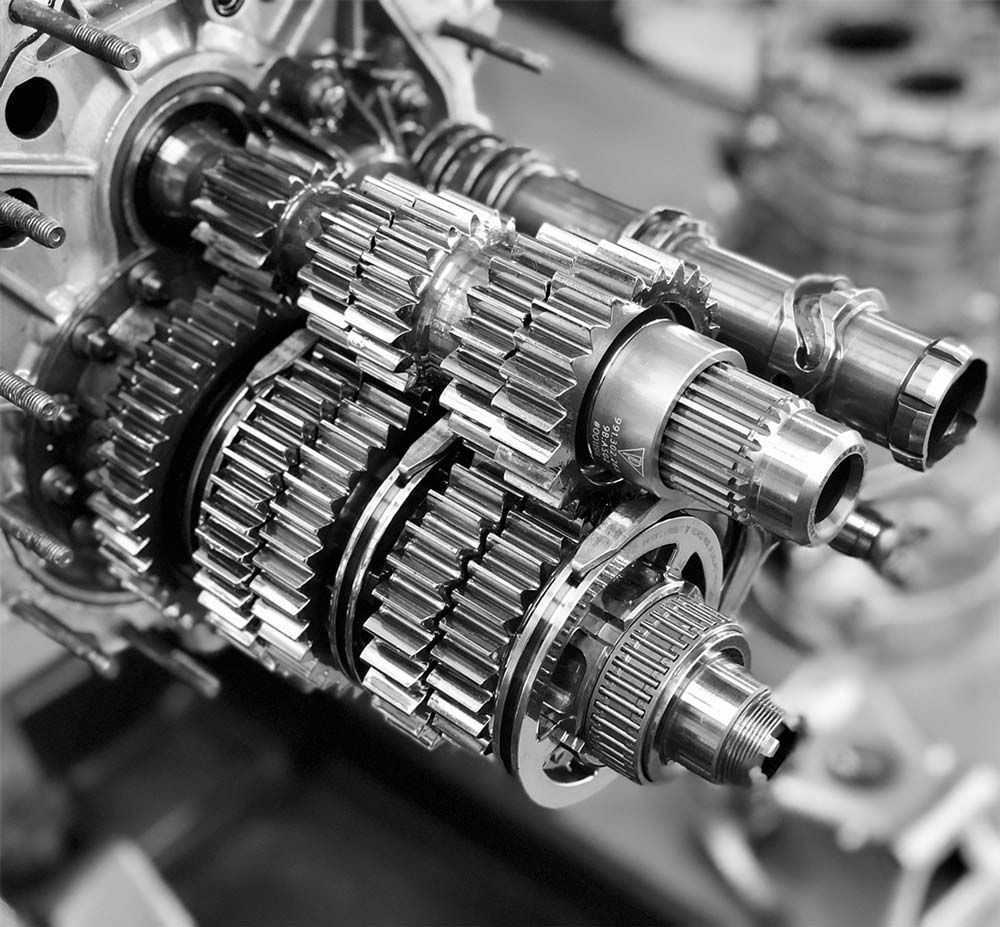 Close-up of a metallic gearbox with interlocking gears and shafts in a machine workshop.