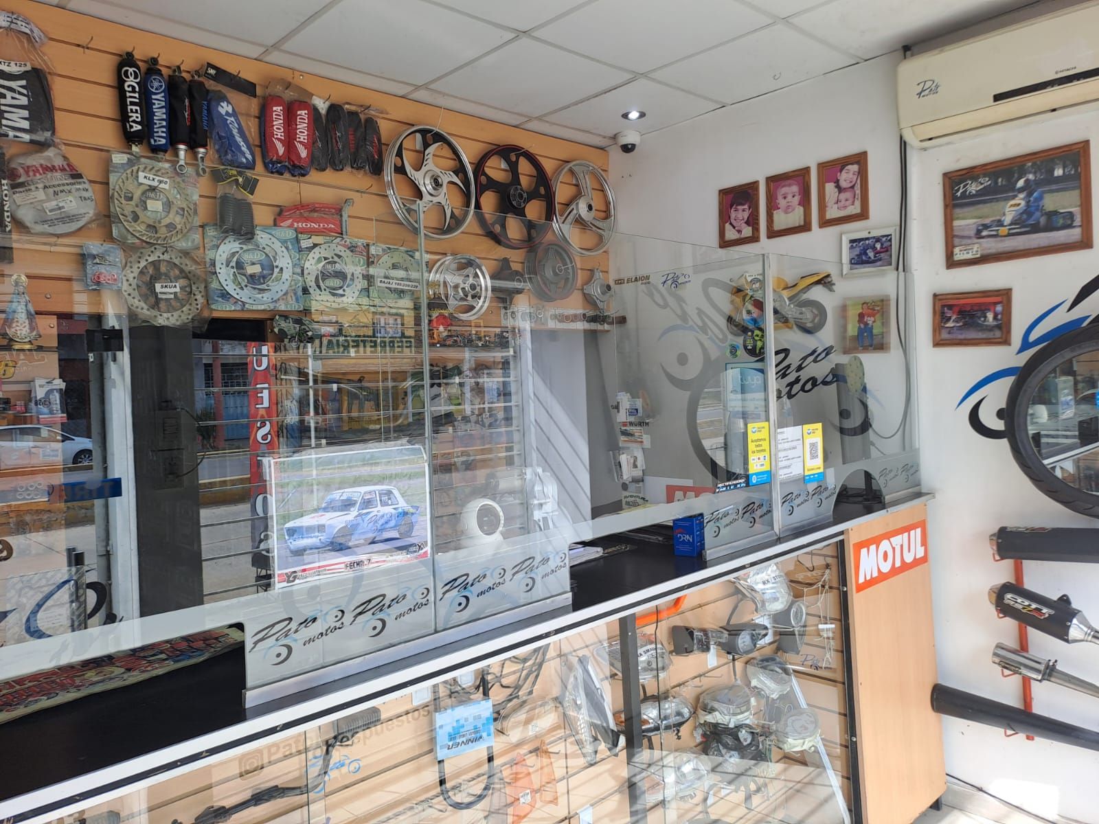 Mostrador de una pequeña tienda con vitrinas, estantes con repuestos y cuadros en las paredes