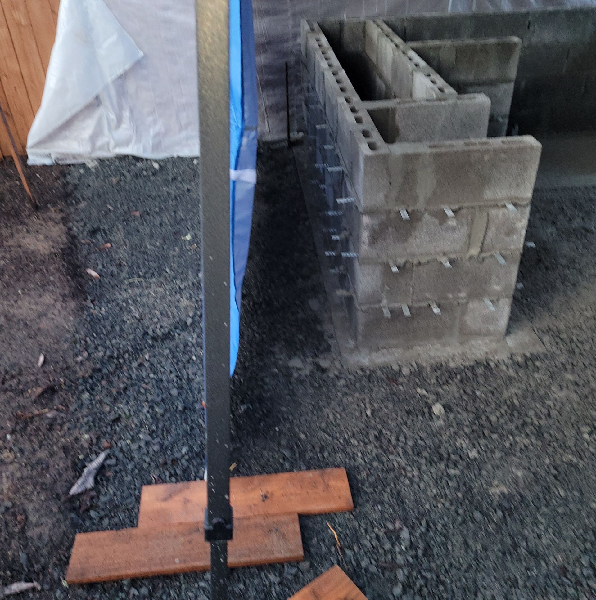 Concrete block wall under construction with a vertical post braced by wooden supports