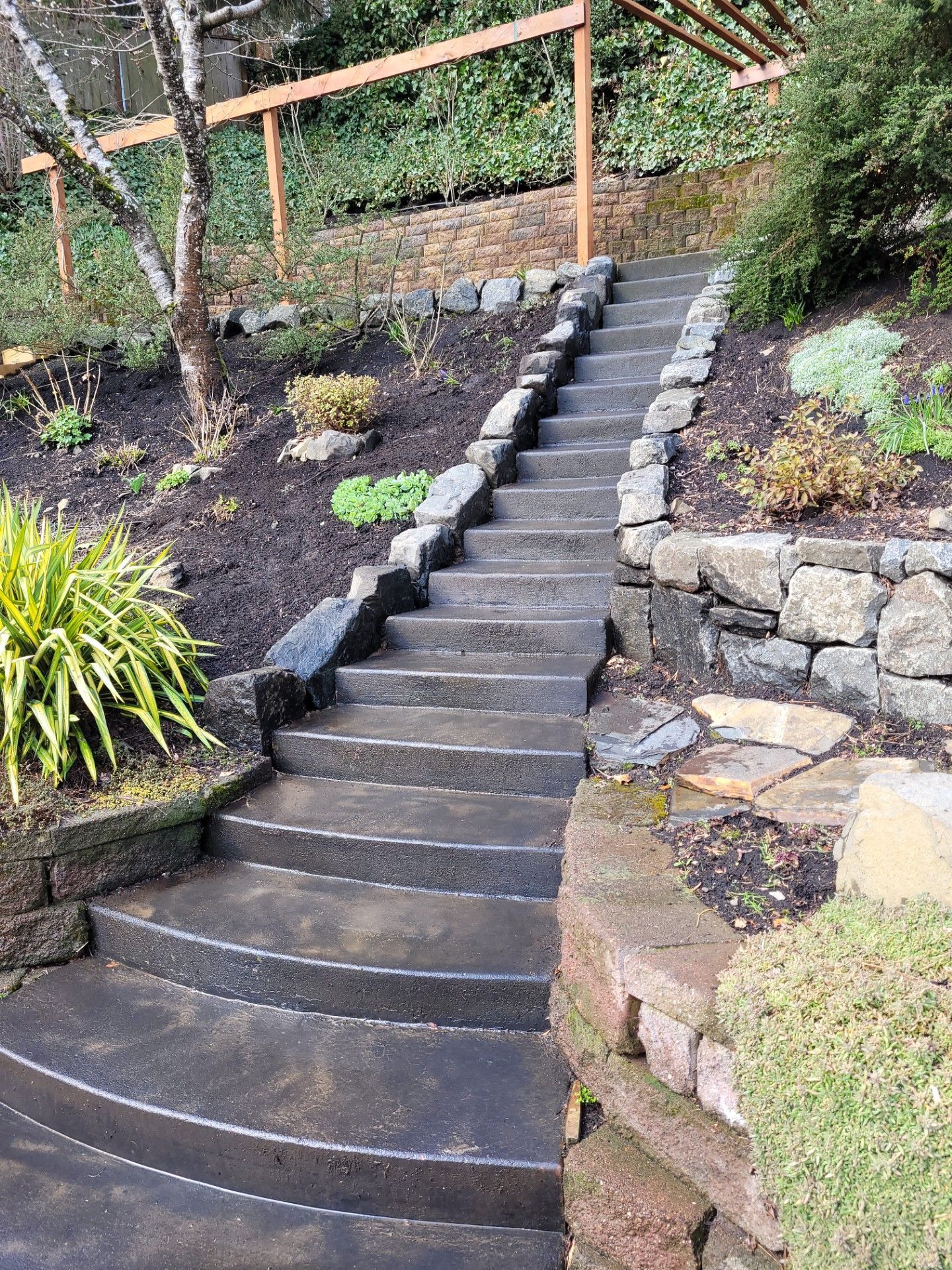 Steep curved stone staircase in a landscaped garden with railings and retaining walls