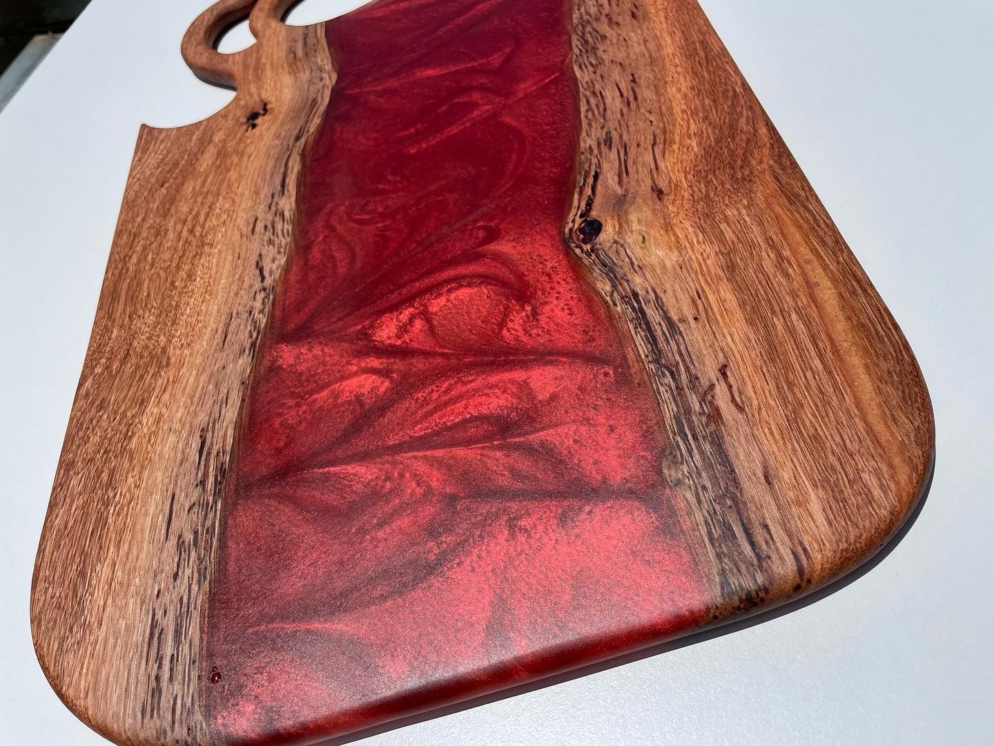 Wooden cutting board with red resin center.