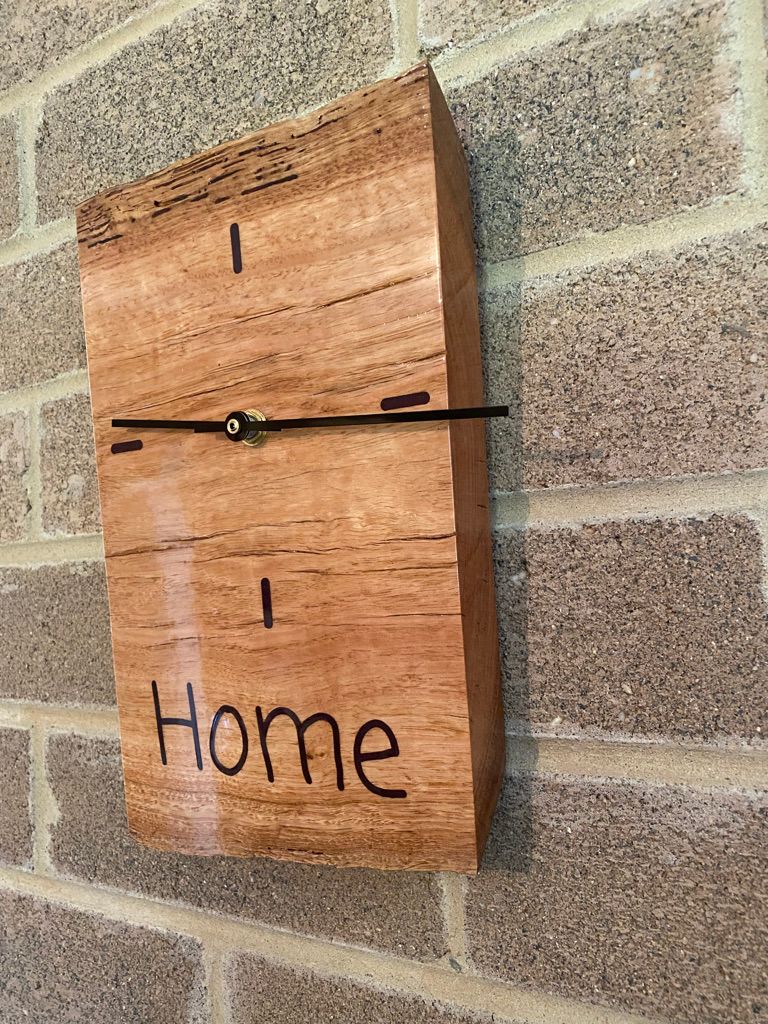 Wooden clock hanging on a brick wall, with 