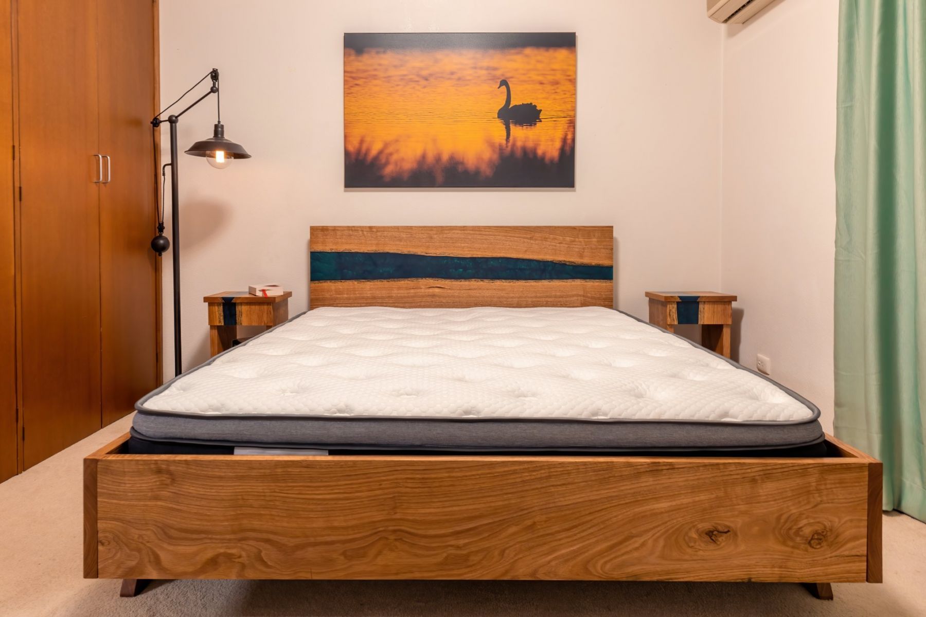 Bedroom with wooden bed, nightstands, mattress, artwork of a swan, and a floor lamp.