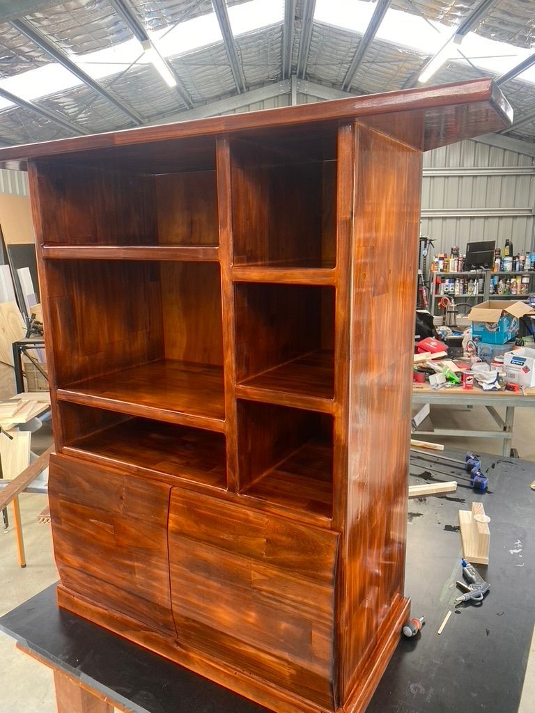 Wooden cabinet with shelves and doors, stained dark brown in a workshop.