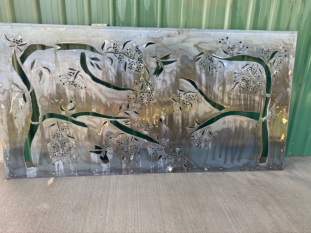 Laser-cut metal panel featuring a bamboo forest design, with cut-out leaves and stems, against a green background.