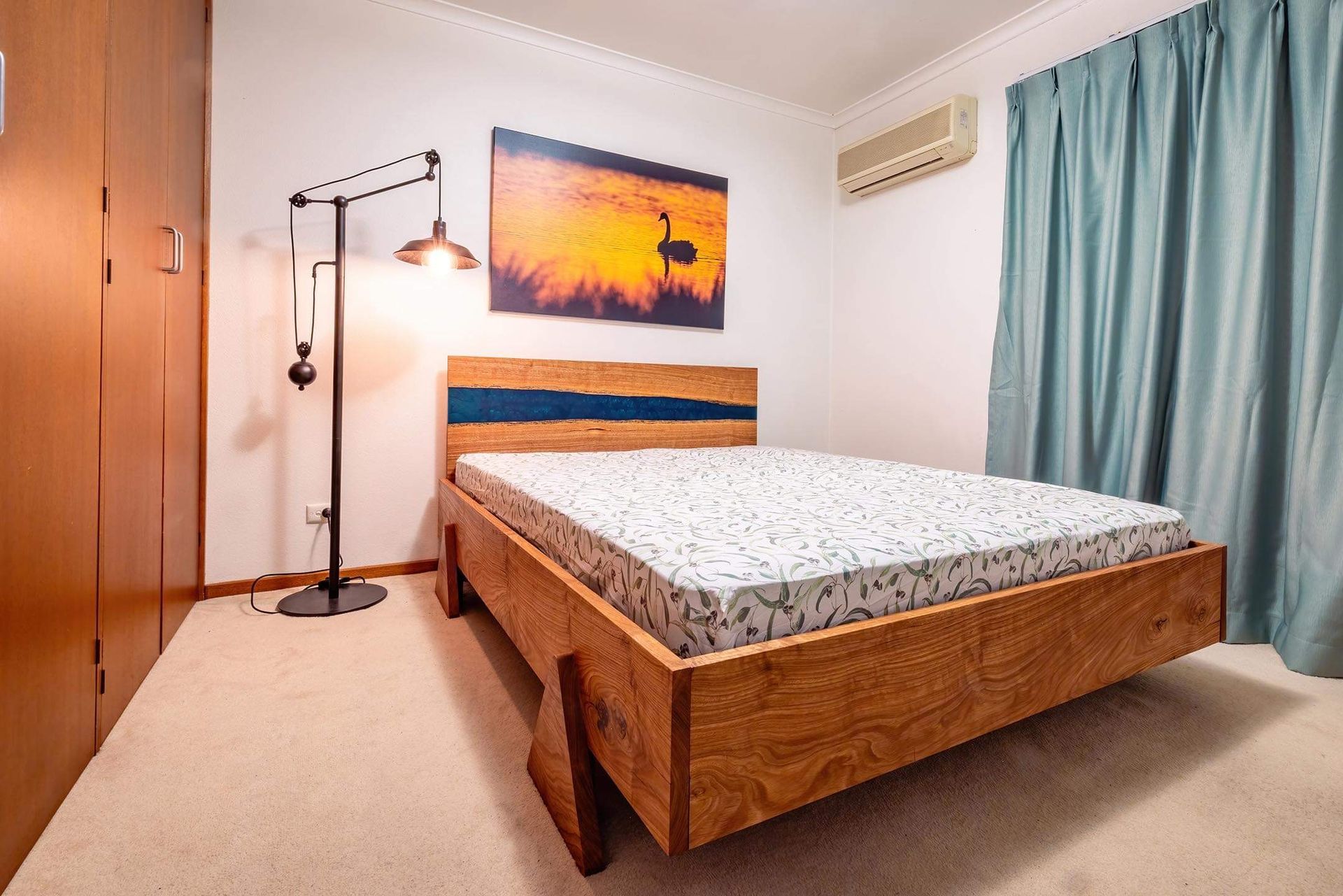A bedroom with a custom wooden bed and a lamp by Metal Wood and Things.