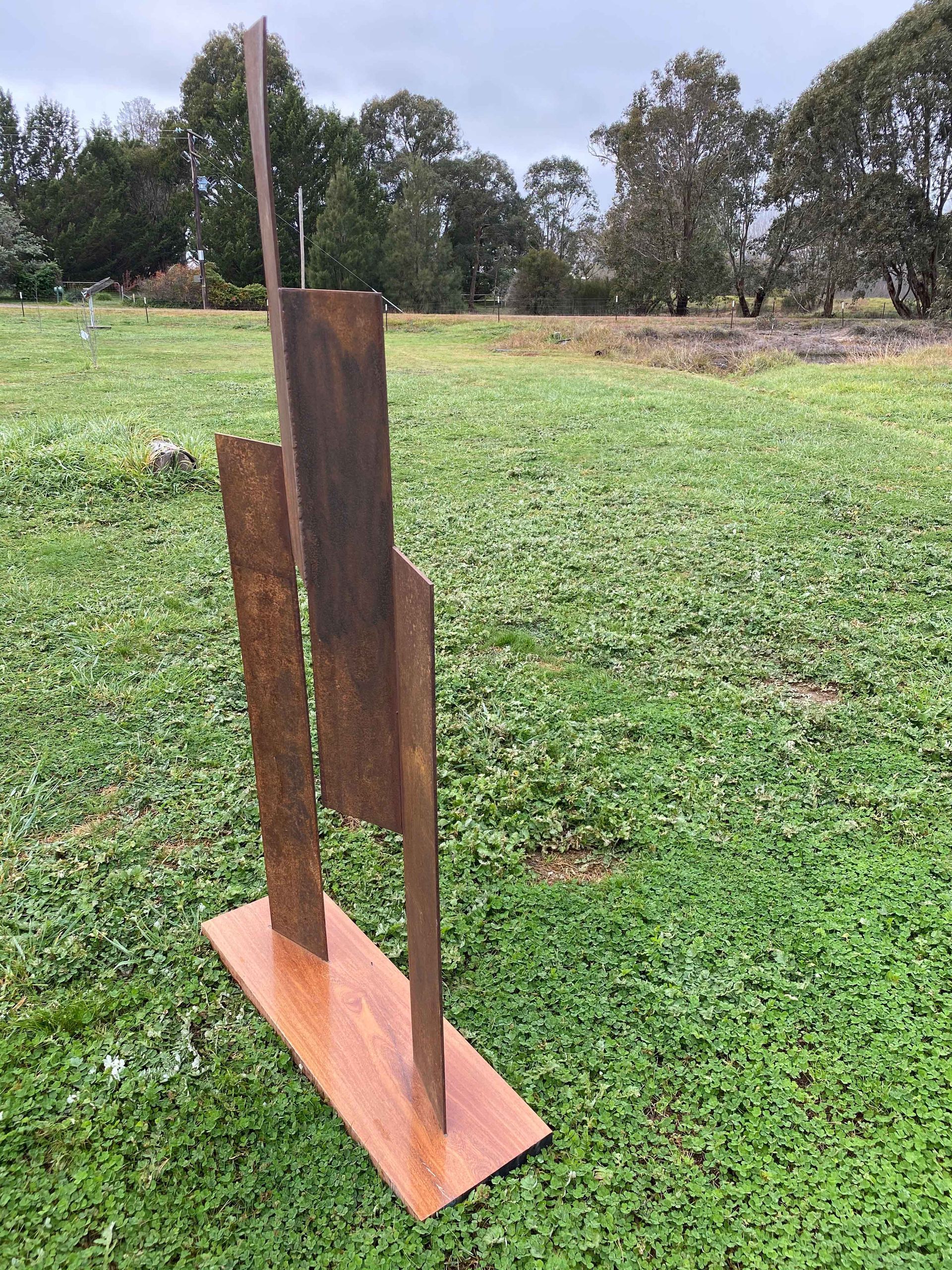 Abstract metal sculpture in a grassy field.