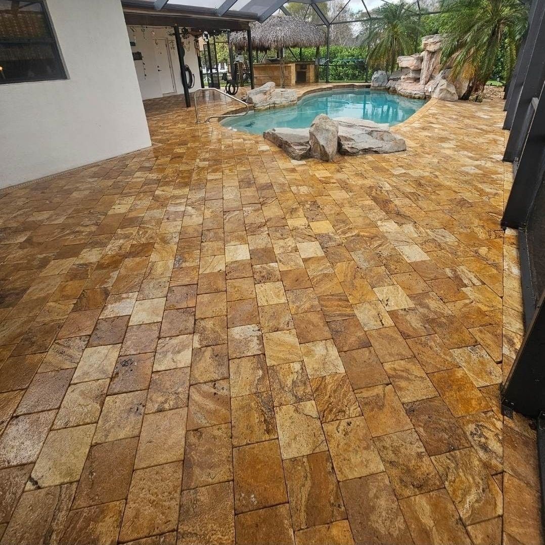 A brick patio with a pool in the background.