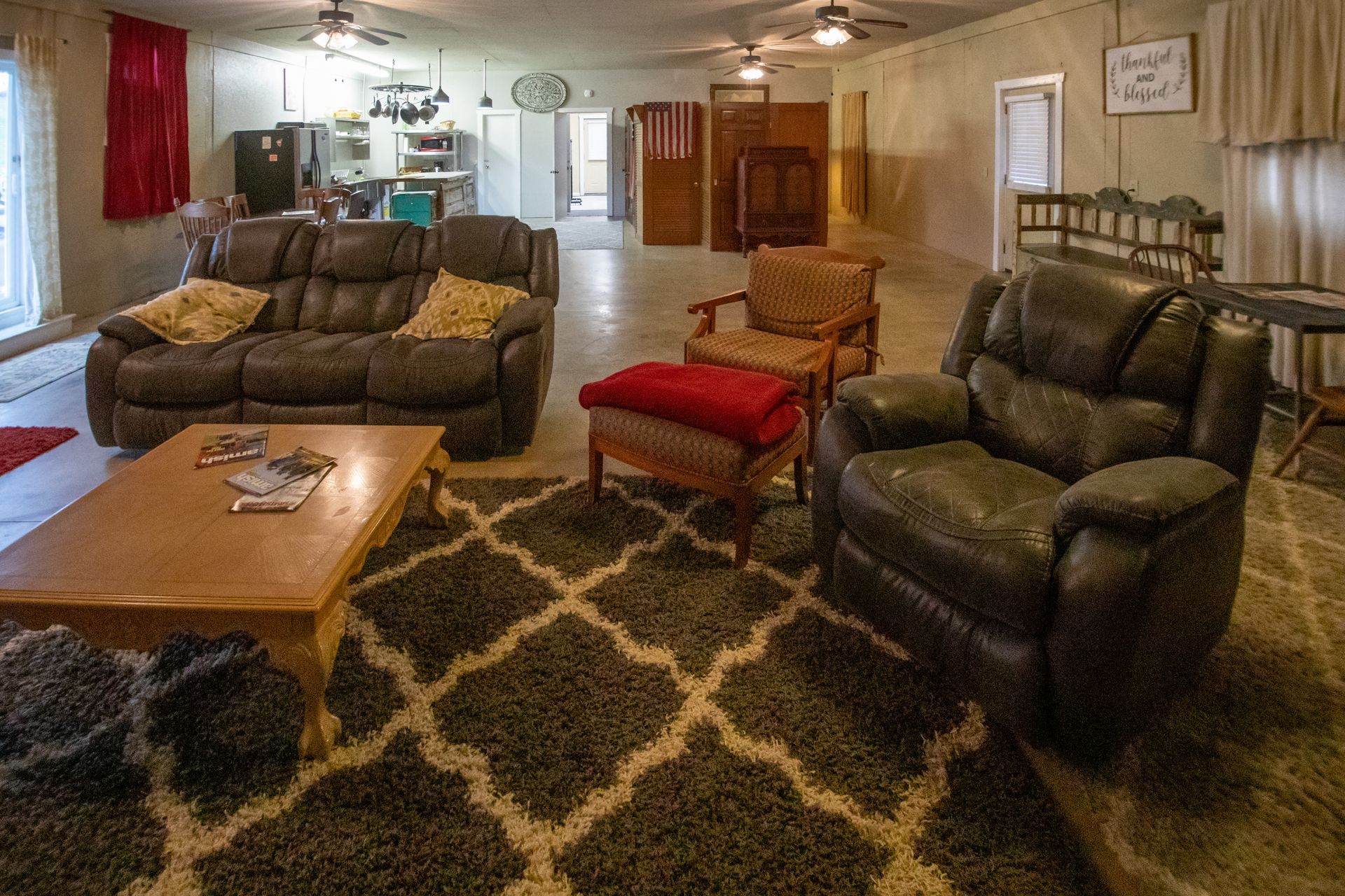 Living room with brown leather furniture, patterned rug, and open doorway to kitchen.