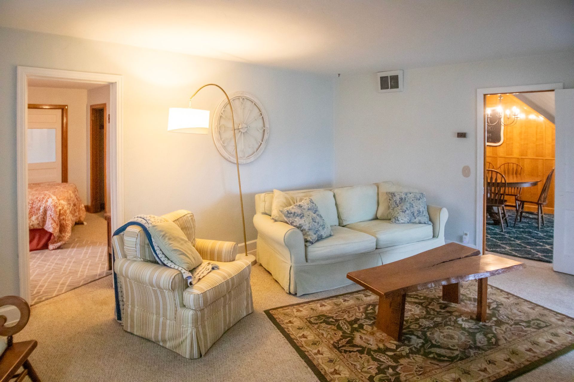 Living room with white walls, beige couch and chair, and a wooden coffee table.