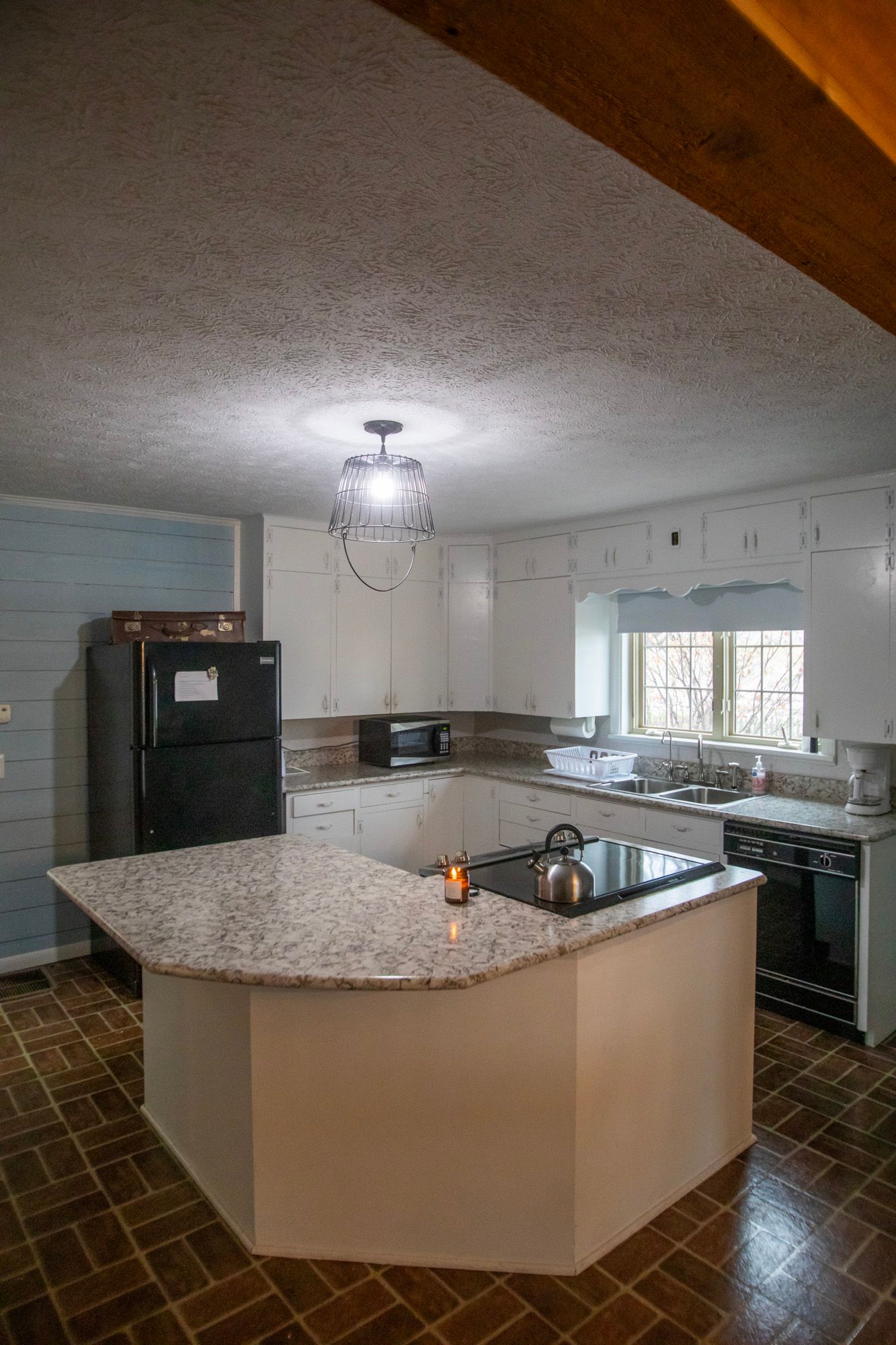 Kitchen with white cabinets, granite countertop, and black appliances.