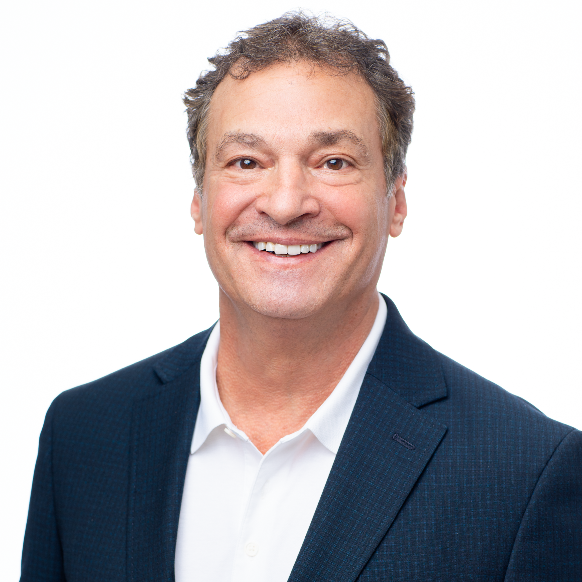 A man in a suit and white shirt is smiling for the camera.