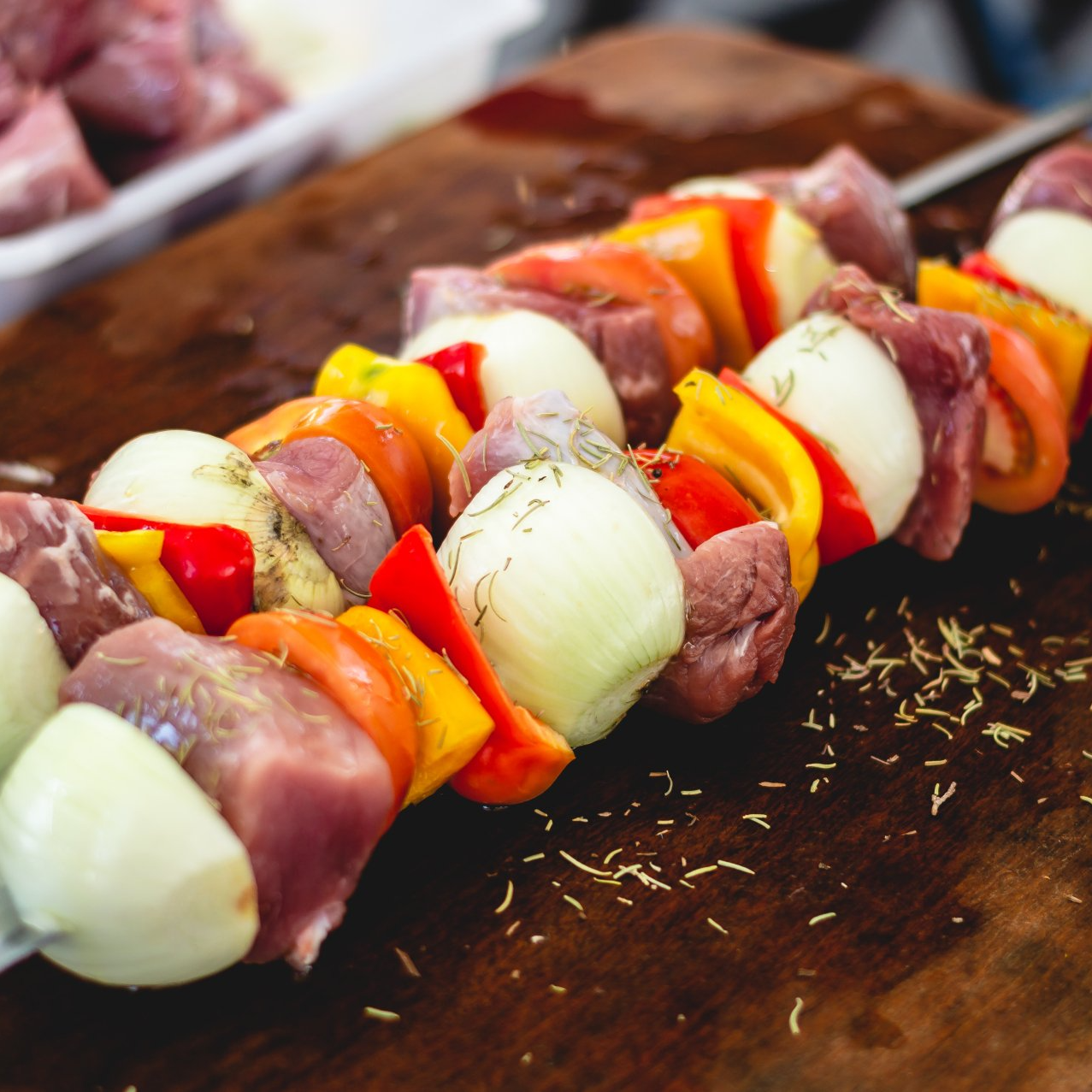 A skewer of meat and vegetables on a cutting board