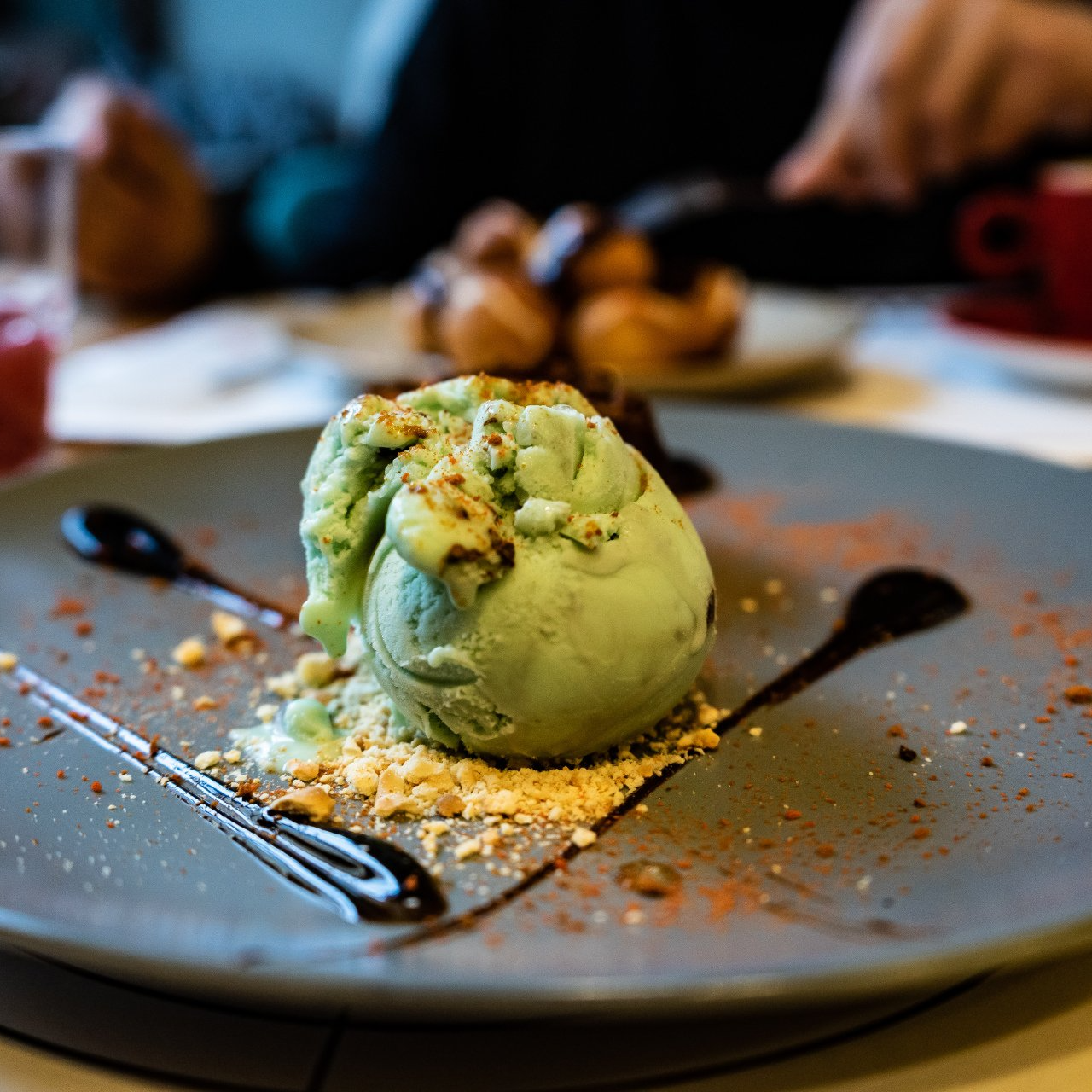 A scoop of green ice cream is on a plate with a fork.