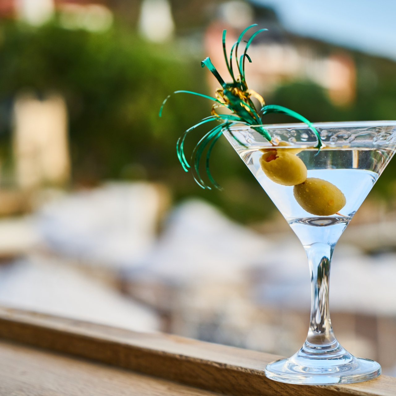 A martini with olives and a green ribbon on top