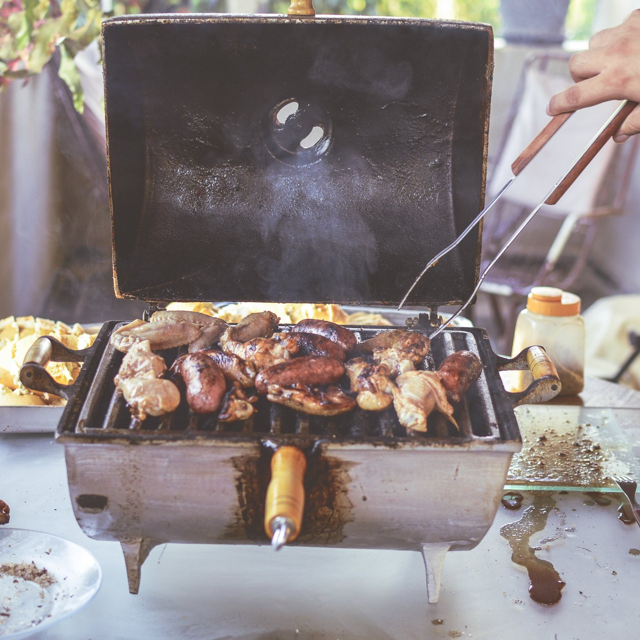 A person is grilling chicken on a grill with tongs