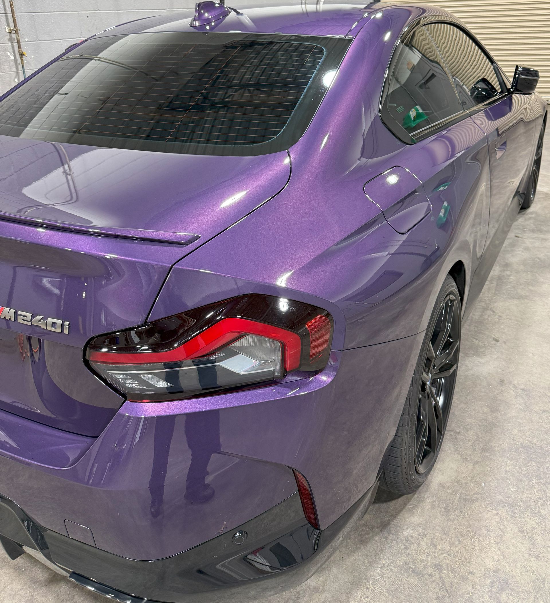 Purple BMW M240i coupe, black wheels, taillight detail, shiny from a ceramic coating