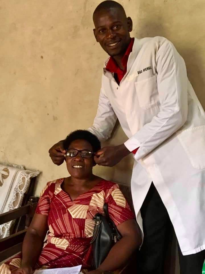 Optometrist fitting eyeglasses on a woman indoors.