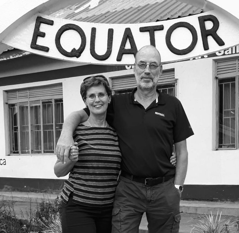 Couple posing under a sign reading