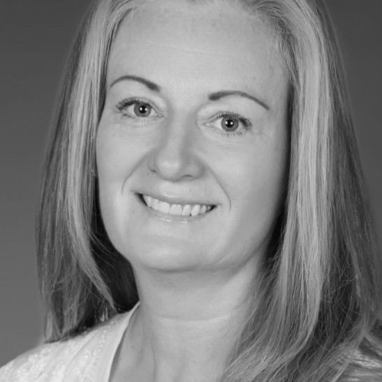Woman with long hair, smiling, looking directly at the camera.