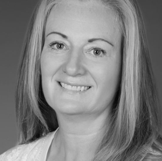 Woman with long hair smiles, posing for a headshot.