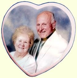 Elderly couple smiling in a heart-shaped portrait with a soft pastel background