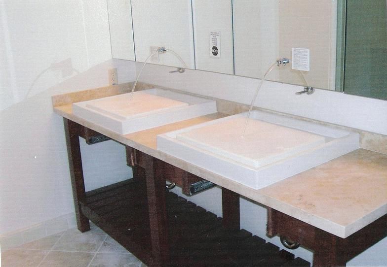 Bathroom with two square sinks set into a beige countertop on a dark wooden vanity. Mirror in the background.